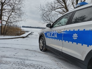 radiowóz przy zamarziętym jeziorze w tle zamarznięte jezior i pomost