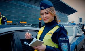 policjantka stoi przy pojazdach w dłoni trzyma notes