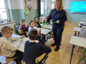 policjantka rozmawia z uczniami w tle sala lekcyjna