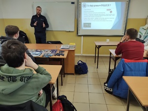 policjant rozmawia z uczniami w tle wyposażenie sali lekcyjnej
