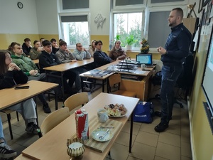 policjant rozmawia z uczniami w tle wyposażenie sali lekcyjnej