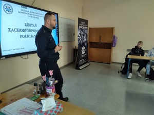 policjant rozmawia z uczniami w tle wyposażenie sali lekcyjnej