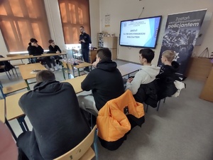 policjant rozmawia z uczniami w tle wyposażenie sali lekcyjnej