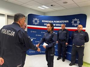 policjanci na tle ścianki z logo Policja