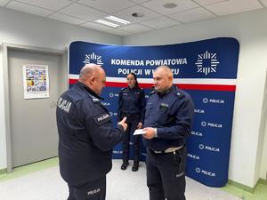 policjanci na tle ścianki z logo Policja