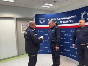policjanci na tle ścianki z logo Policja