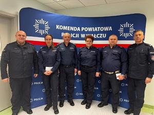 policjanci na tle ścianki z logo Policja