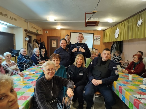 policjanci rozmawiają z seniorami w tle policjanci i seniorzy