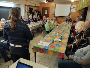 policjanci rozmawiają z seniorami w tle policjanci i seniorzy
