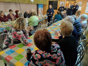 policjanci rozmawiają z seniorami w tle policjanci i seniorzy
