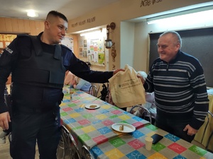policjanci rozmawiają z seniorami w tle policjanci i seniorzy