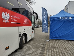 krwiobus obok namiot i flaga z napisem Policja
