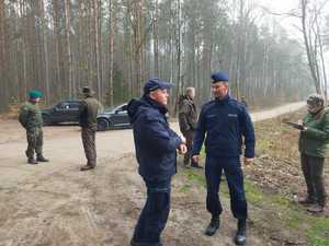 policjanci i inne służby sadzą młode drzewka w tle las i inne ososby