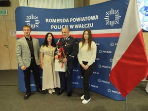 wspólne zdjęcie komendanta z rodziną  w tle ścianka z logo policji Wałcz
