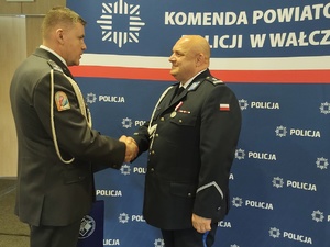 składanie życzeń przez wojskowego w tle ścianka z logo policji