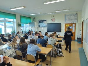 policjantka rozmawia z uczniami w tle sala lekcyjna