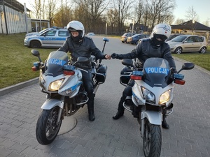 dwóch policjantów na słuzbowych motocyklach w tle parking