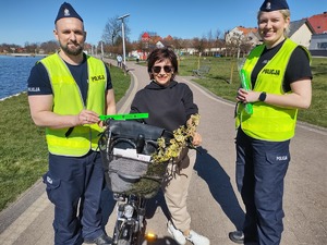 policjanci wręczają odblaski rowerzystom w tle promenada jeziora