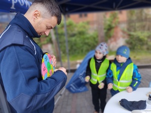policjanci zabawiają dzieci zabawami edukacyjnymi w tle namiot policyjny i dzieci
