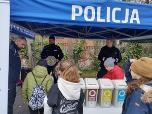 policjanci zabawiają dzieci zabawami edukacyjnymi w tle namiot policyjny i dzieci