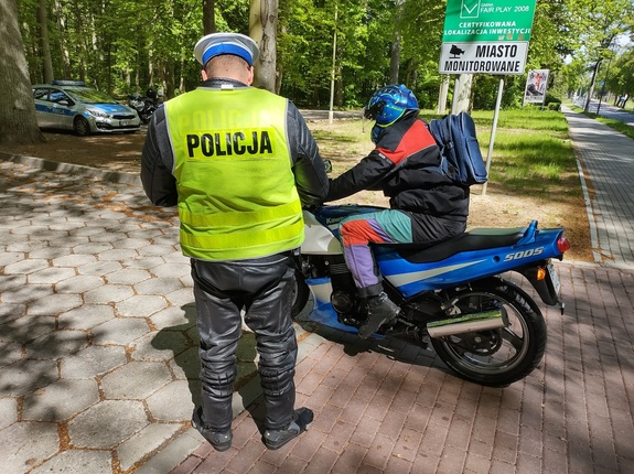 policjant kontroluje motocyklistę w tle las i droga