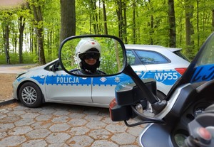 policjant kontroluje motocyklistę w tle las i droga