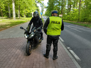 policjant kontroluje motocyklistę w tle las i droga