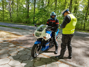 policjant kontroluje motocyklistę w tle las i droga