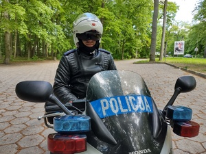 policjant kontroluje motocyklistę w tle las i droga