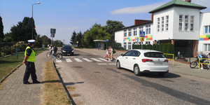 policjantka obserwuje ruch drogowy w tle szkoła i piesi