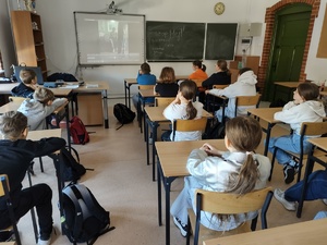 uczniowie oglądają film w tle film na tablicy