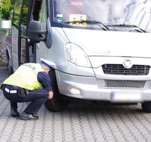 Policjant sprawdza ogumienie autobusu