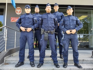 policjanci stoją na schodach przed wejściem do budynku komendy w tle drzwi