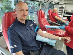 policjant oddaje honorowo krew w tle wyposażenie krwiobusa