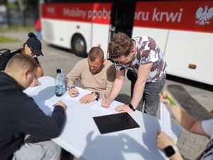 policjant oddaje honorowo krew w tle wyposażenie krwiobusa