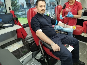 policjant oddaje honorowo krew w tle wyposażenie krwiobusa