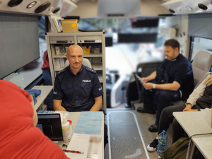 policjant oddaje honorowo krew w tle wyposażenie krwiobusa
