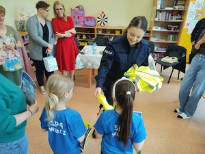 policjantka wręcza kamizelki w tle goście i sala