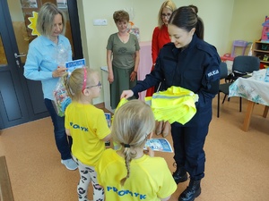 policjantka wręcza kamizelki w tle goście i sala