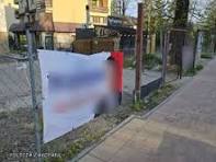 baner wiszący na ogrodzeniu w tle budynki