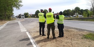 służby stoją przy drodze w tle ulica i jadący Tir