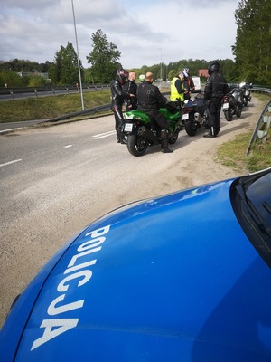 policjant kontroluje motocyklistę w tle droga