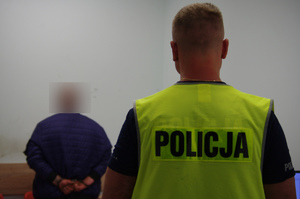 kraty więzienne za nim policjant i osoba zatrzymana