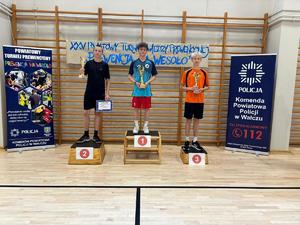 trzej zawodnicy na podium w tle banery i drabinki