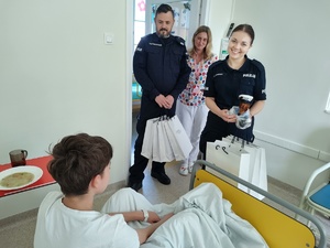 policjanci wręczają paczki w tle sala szpitalna