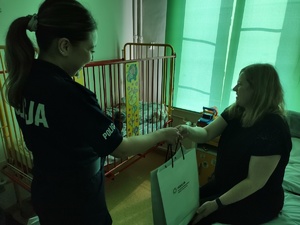 policjanci wręczają paczki w tle sala szpitalna