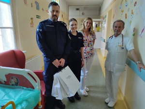 policjanci wręczają paczki w tle sala szpitalna