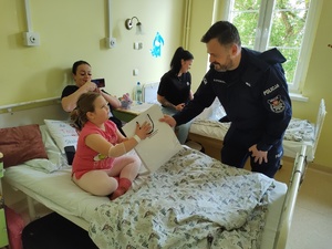 policjanci wręczają paczki w tle sala szpitalna