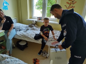 policjanci wręczają paczki w tle sala szpitalna