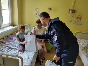 policjanci wręczają paczki w tle sala szpitalna
